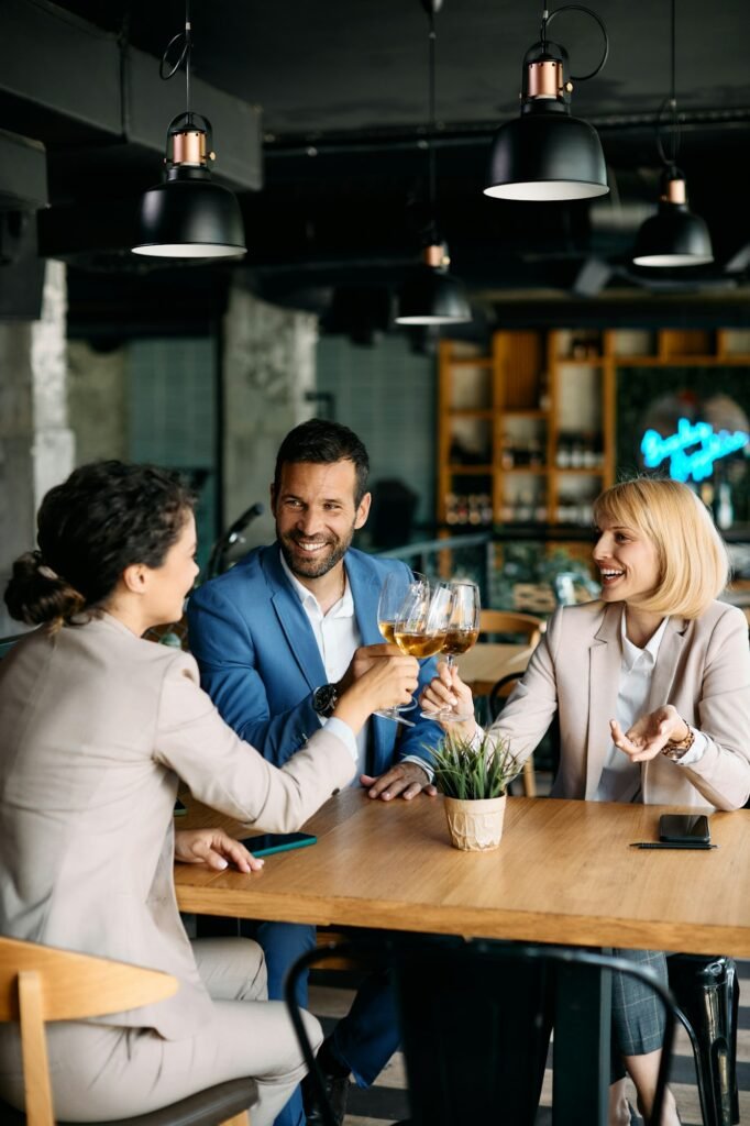 Group of cheerful business colleagues toasting with wine in a cafe.